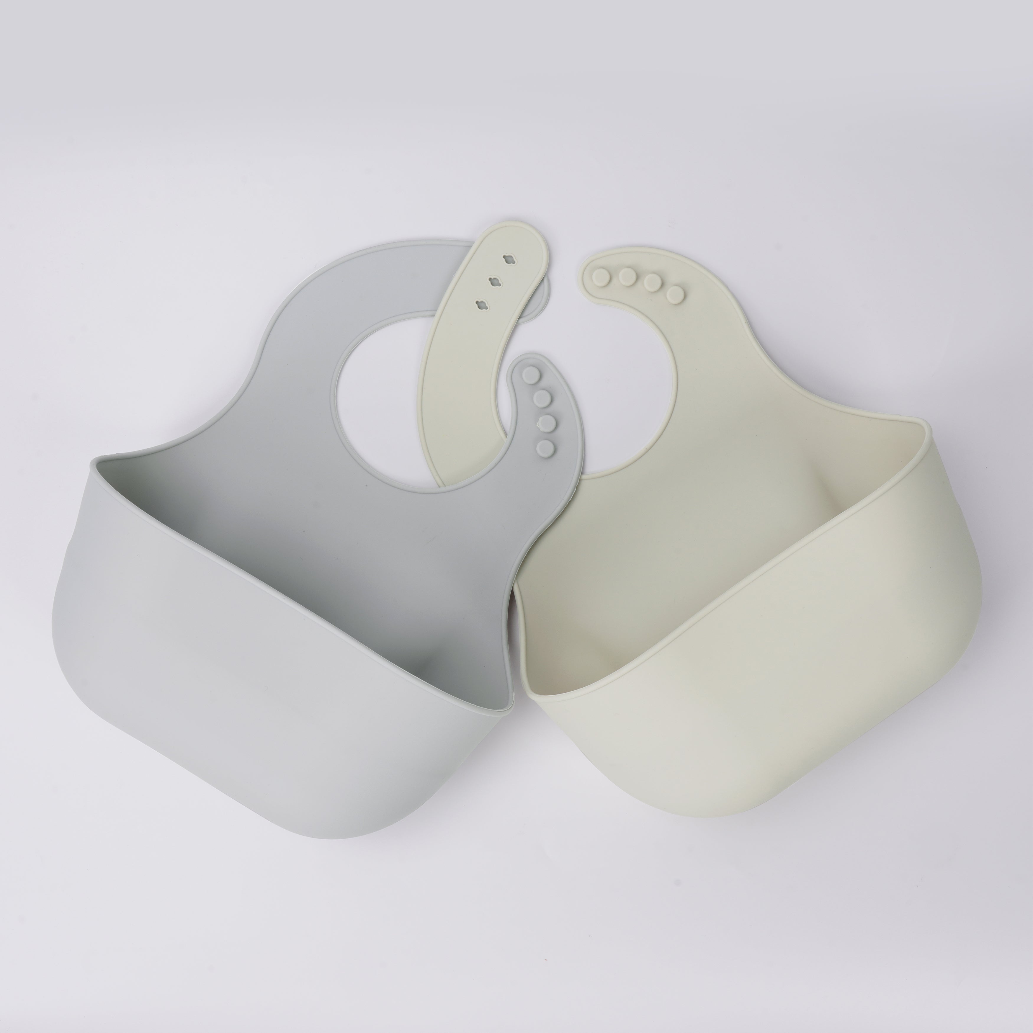Two YOBIB travel sickness bibs in grey and beige, arranged horizontally, showing deep catch pockets and flexible silicone on a light grey background.