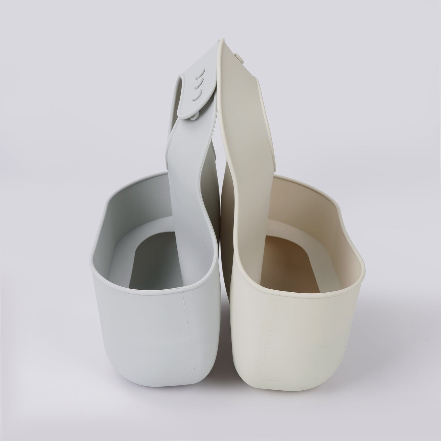 Two YOBIB travel sickness bibs in beige and grey, stacked side-by-side, showing deep catch pockets and adjustable neck straps on a white background.